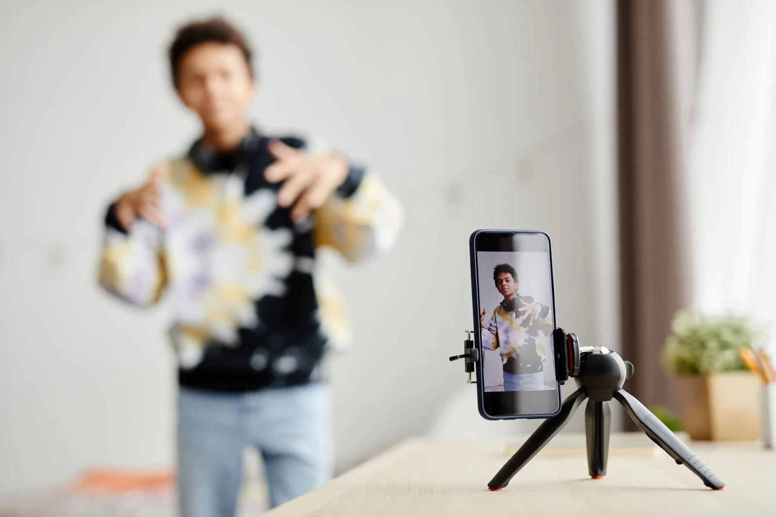 Creator recording a video at home with a smartphone on a tripod